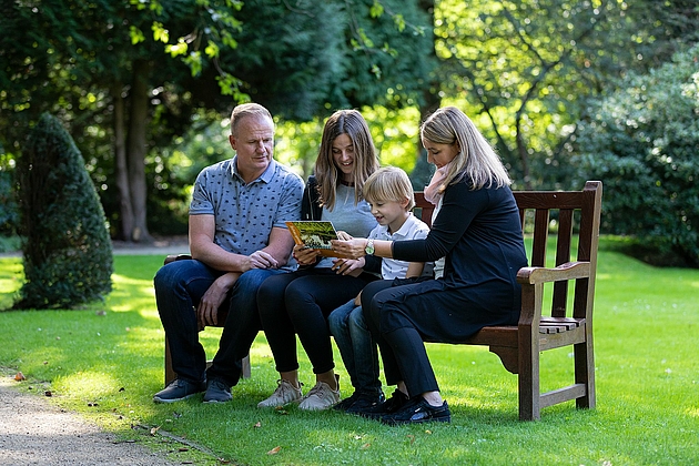 Familie verweilt auf einer Parkbank im Schlosspark