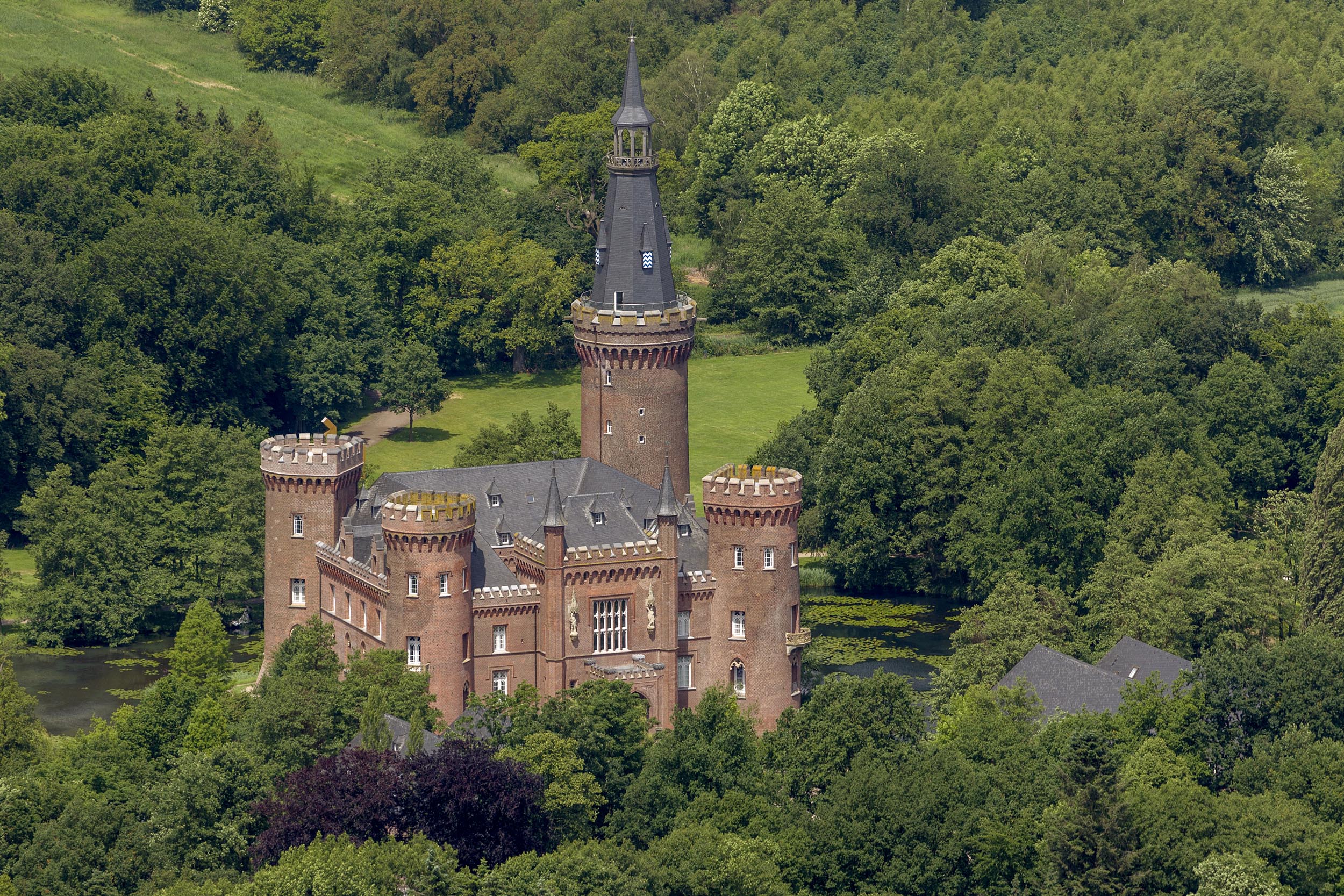 Schloss Moyland von oben, eingebettet in Wald und Wiese